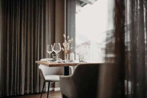 a table with wine glasses on it next to a window at Hotel VIEW - incl Joker Card in Summer in Saalbach Hinterglemm