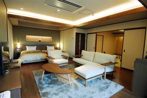 a hotel room with a bed and a living room at Arima Onsen Taketoritei Maruyama in Kobe