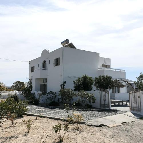 a white house with a fence in front of it at Sagma Central Rooms in Perissa