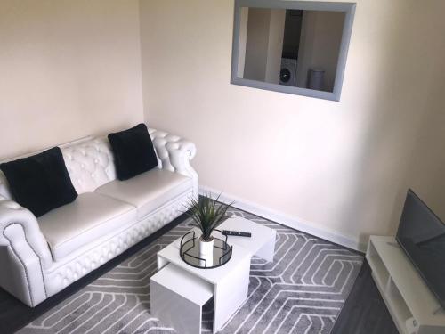 a living room with a white couch and a tv at Vogue Apartments in Glasgow