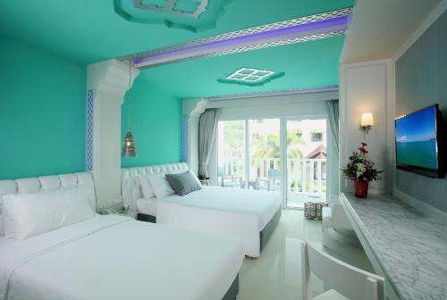 a blue bedroom with two beds and a tv at The Verandah - SHA Extra Plus in Ao Nang Beach