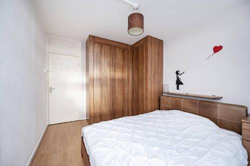 a bedroom with a white bed and a wooden cabinet at 1-double bedroom aparment in Central London in London