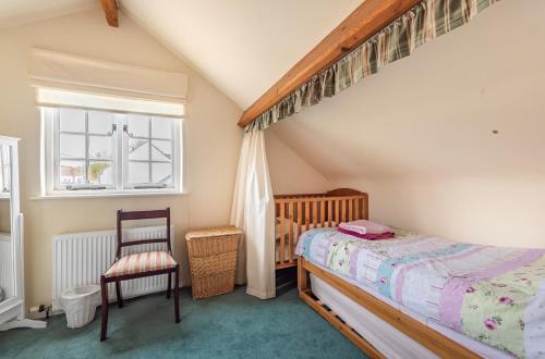 een slaapkamer met een bed, een stoel en een raam bij Heydons House - Lovely Seaside Cottage in Sidmouth