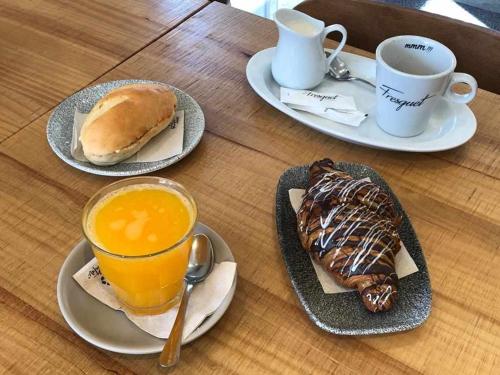 a table with two plates of food and a cup of orange juice at Rincón en la playa by Rinconesmediterraneos in L'Eucaliptus