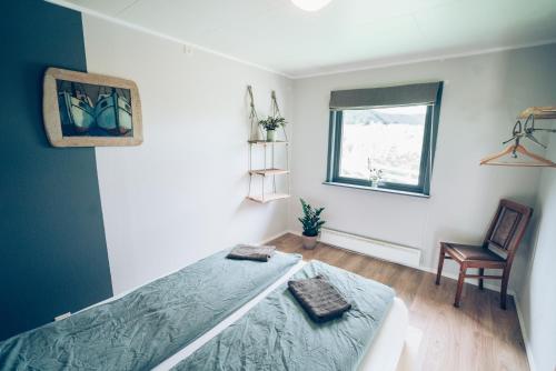 a bedroom with a bed and a window and a chair at FURU Hostel & Café in Bøstad