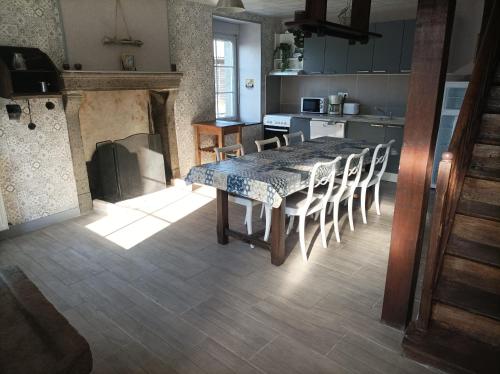 eine Küche mit einem Tisch mit Stühlen und einem Kamin in der Unterkunft Gite Auvraysien 10p in La Forêt-Auvray