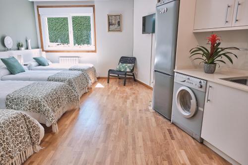 a living room with two beds and a washing machine at Pensión A Solaina in O Pedrouzo