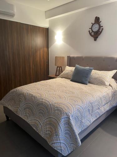 a bedroom with a bed with a clock on the wall at Departamento bellísimo a 10 minutos de la playa in Nuevo Vallarta