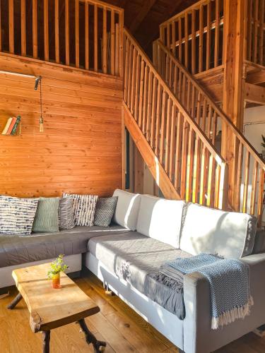 a living room with a couch and a staircase at THE HOUSE IN THE OAKS הבית באלונים in Amirim