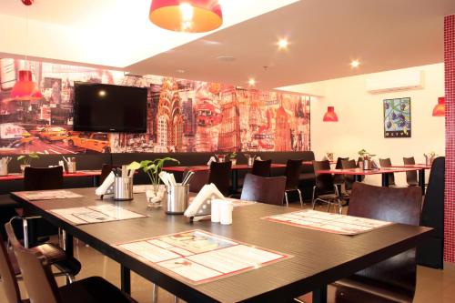 a dining room with a table and chairs and a tv at Red Fox by Lemon Tree Hotels, Jaipur in Jaipur