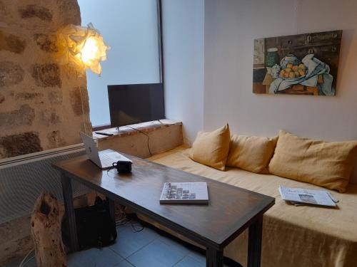 un salon avec un canapé et une table avec un ordinateur portable dans l'établissement Consulat Figeac, à Figeac