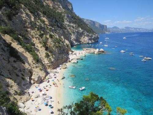 a beach with people and boats in the water at Appartamento Mariolu 3 in Santa Maria Navarrese