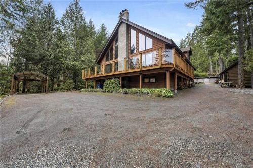 ein großes Haus mit großer Auffahrt davor in der Unterkunft Chalet Style Cottage near Shawnigan Lake in Shawnigan Lake