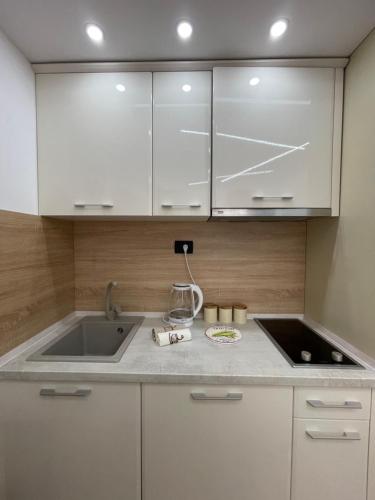 a kitchen with white cabinets and a sink at Lasadu Studio in Casa Al Mare, 2 min to Beach in Bečići
