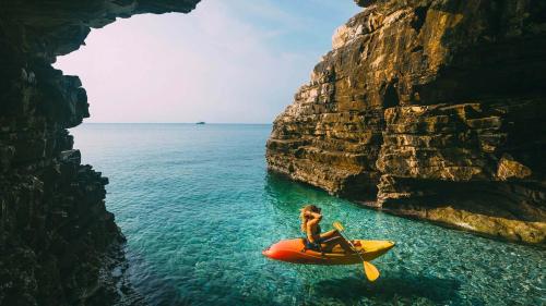a woman riding a kayak in the water next to a cliff at Penthouse Gea in Premantura