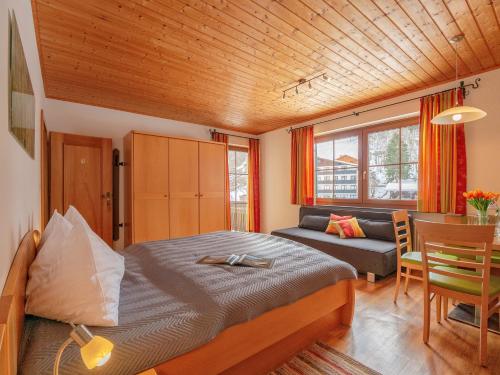 een slaapkamer met een bed, een tafel en een bank bij Landhaus Schwaiger in Bad Hofgastein