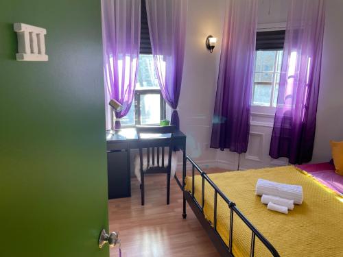 a bedroom with a bed and a desk and purple curtains at Chambres EL MEDITERRANEO Rooms in Montréal