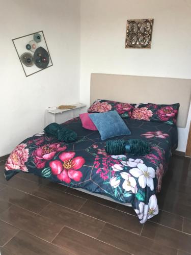 a bedroom with a bed with a floral comforter at HACIENDA LA MACARENA DE SEVILLA in Cantillana