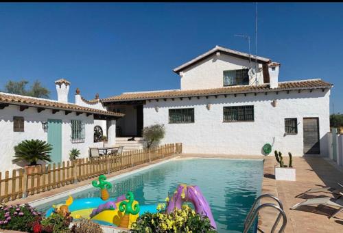 a house with a swimming pool in front of a house at HACIENDA LA MACARENA DE SEVILLA in Cantillana