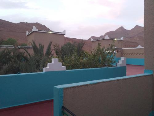 a house with a blue fence and mountains in the background at Kasbah Hotel Camping Jurassique in Ifri