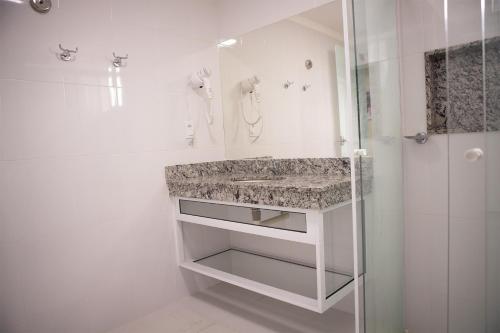 a white bathroom with a sink and a shower at CD PIAZZA COM ACQUA PARK in Caldas Novas