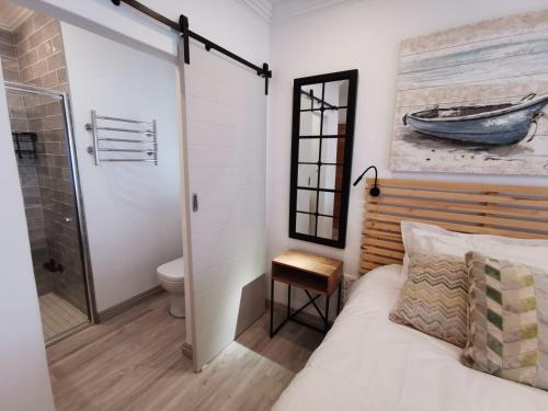 a bedroom with a bed and a bathroom with a toilet at Nearby Herolds Bay Self-Catering Guest House in Herolds Bay