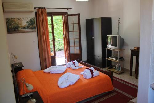 a bedroom with an orange bed with towels on it at Artemis Apartments in Konitsa