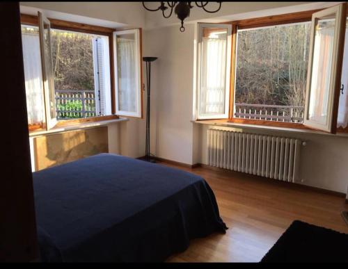 um quarto com duas janelas e uma cama. em Appartamento in villa sulle colline di Torino em Turim