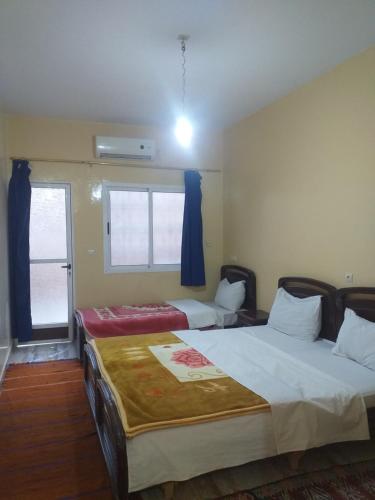 two beds in a room with a window at Kasbah Hotel Camping Jurassique in Ifri