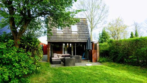 a backyard with a house with a couch and a tree at Oude-Tonge holiday house near fishing waters in Oude-Tonge
