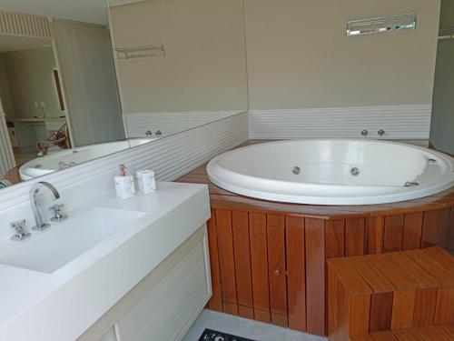 a bathroom with a large tub and a sink at Nova Onda Hotel in Cabo Frio