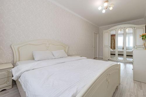 um quarto branco com uma cama grande e lençóis brancos em Apartments 7 Я-14 em Astana
