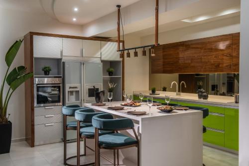 a kitchen with green cabinets and a white island with bar stools at Maison De Mare, 4BR Central Luxury Beach Residence in Hersonissos