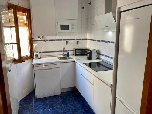 una pequeña cocina blanca con fregadero y nevera en Blue Corredera Vejer, en Vejer de la Frontera