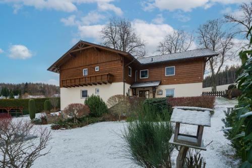 a large wooden house with snow on the ground at Penzion U Černého kohoutka in Zdíkov