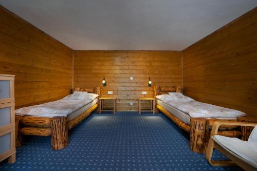 a room with two beds in a wooden room at Penzion U Černého kohoutka in Zdíkov