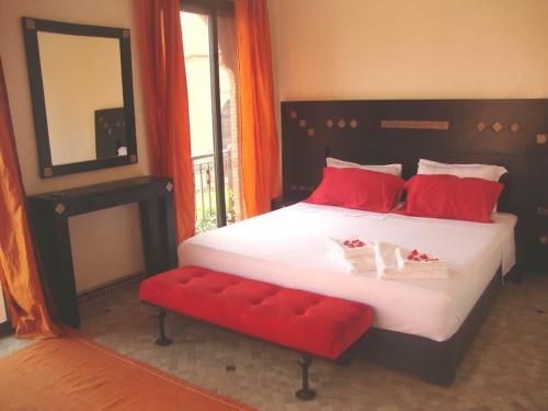 Un dormitorio con una cama grande con almohadas rojas y un banco rojo. en VILLA Garden, en Marrakech