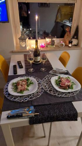 a table with two plates of food and a bottle of wine at Apartma Marjetica in Gozd Martuljek