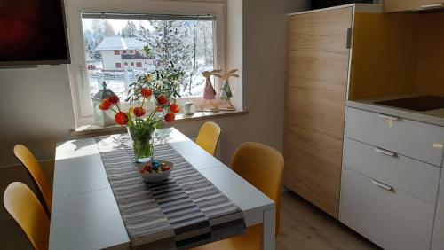 a kitchen table with a vase of flowers on it at Apartma Marjetica in Gozd Martuljek