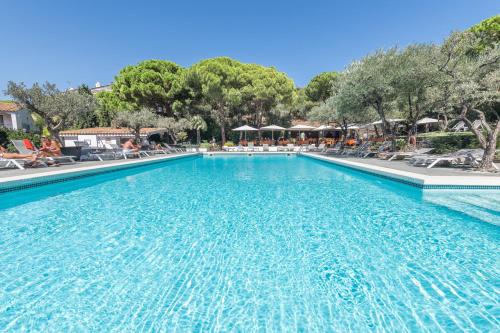 una piscina en un complejo con sillas y árboles en Hotel Playa Sol, en Cadaqués