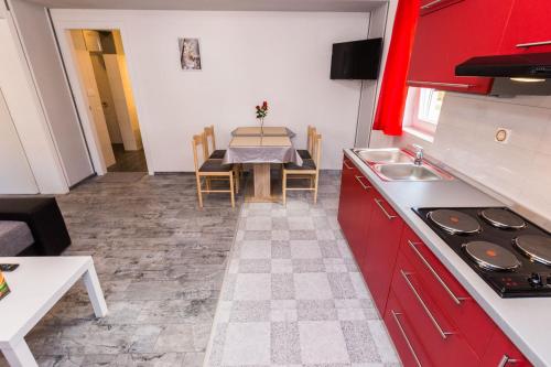 a kitchen with red cabinets and a table with a sink at Apartments Lemmy in Zadar