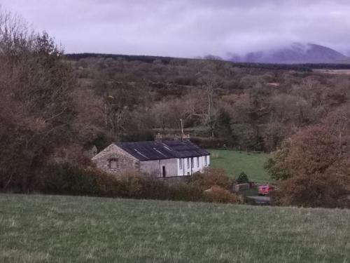 a house in a field with a mountain in the background at Rainors farm B&B in Gosforth