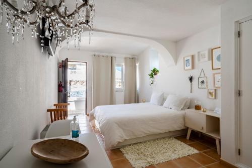 a white bedroom with a bed and a table at Vivenda Brito in Carvoeiro