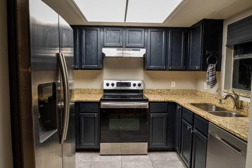una cocina con armarios negros y electrodomésticos de acero inoxidable en Renovated 3 Br home near all main attractions en Kissimmee