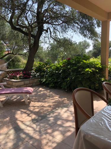 a patio with a table and chairs and a tree at Apartmani Anamar in Supetarska Draga