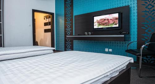 a bedroom with two beds and a tv on a wall at Hotel Polo in Prešov