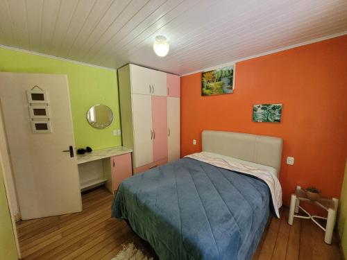 1 dormitorio con paredes de color naranja y verde y 1 cama en lugar tranquilo aconchegante perto da natureza, en Nova Petrópolis