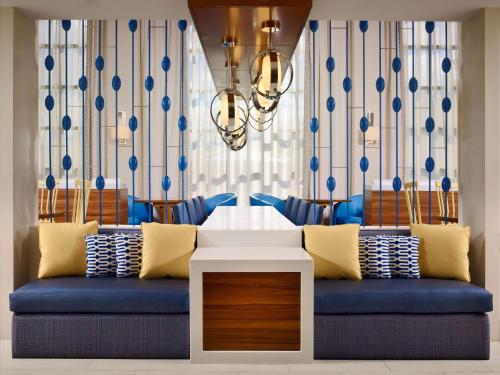 Sonesta ES Suites Somerset في سومرست: غرفة معيشة بها أريكة زرقاء وثريا