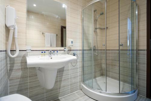 ein Bad mit einem Waschbecken und einer Glasdusche in der Unterkunft Grenada Hotel in Sonnenstrand