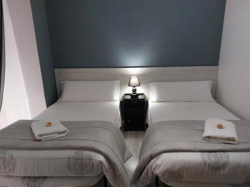 a room with two beds and a table with a lamp at Pensión Saint Mateo in Logroño